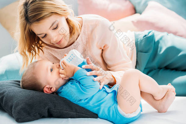 母亲在家里的床上<strong>喂养</strong>孩子的婴儿奶瓶
