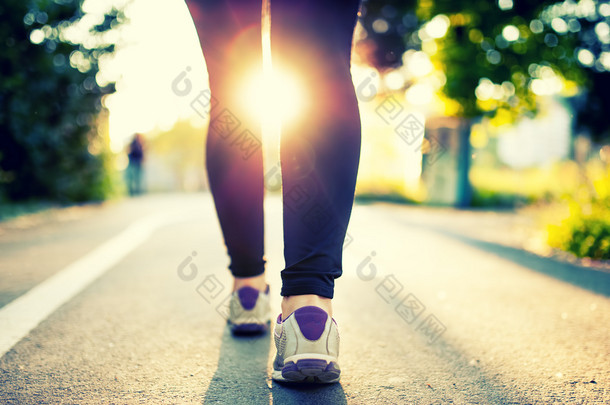 女子运动员脚和鞋在公园跑步时的特写镜头。健身理念和城市公园里小跑的女运动员福利