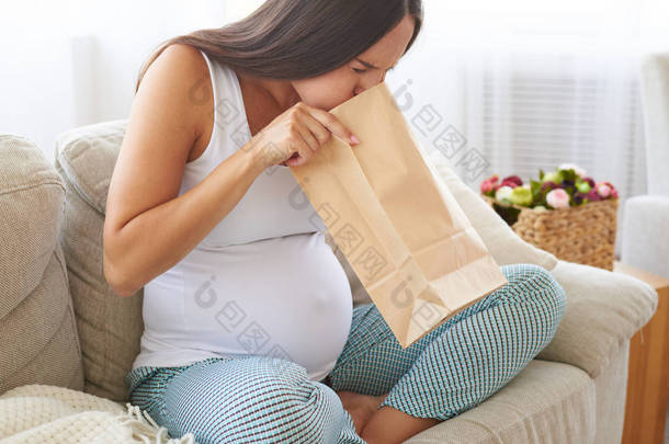 怀孕的女人觉得恶心使用纸袋空气