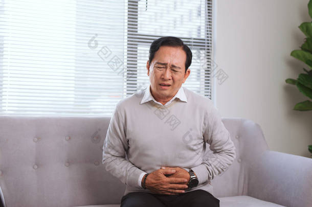坐在沙发上的亚洲老人胃痛老人健康老年人健康