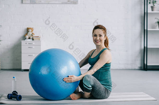 美丽的怀孕妇女坐在<strong>瑜伽</strong>垫与<strong>健身球</strong>在客厅里