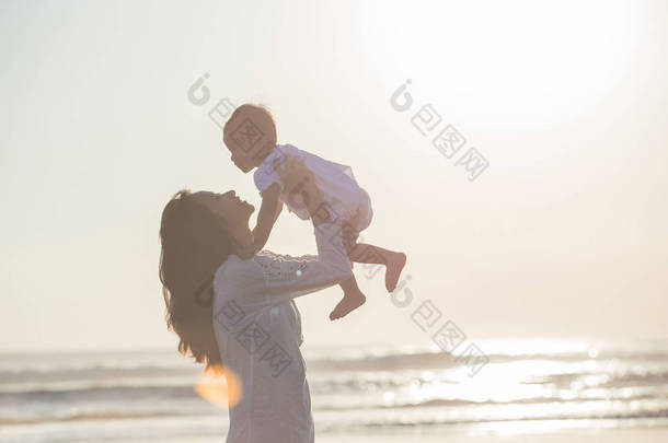妈妈和宝宝在日落海滩的肖像
