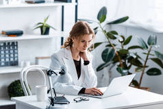 专注的女商人在正式穿坐在办公桌前, 并在工作场所使用笔记本电脑