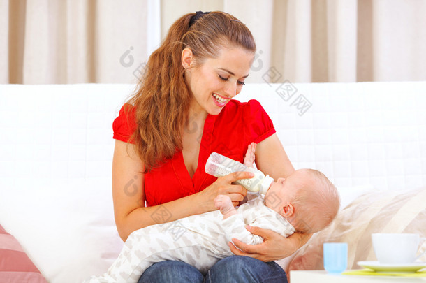 快乐妈妈坐在沙发上和喂养宝宝