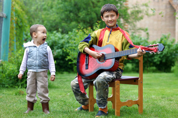两个有趣的男孩子学音乐的学生演唱、 演奏吉他 outd