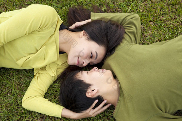 亚洲对年轻夫妇在草地上的爱