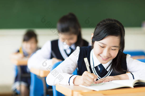 微笑在教室里的学生女孩和她的朋友在背景中