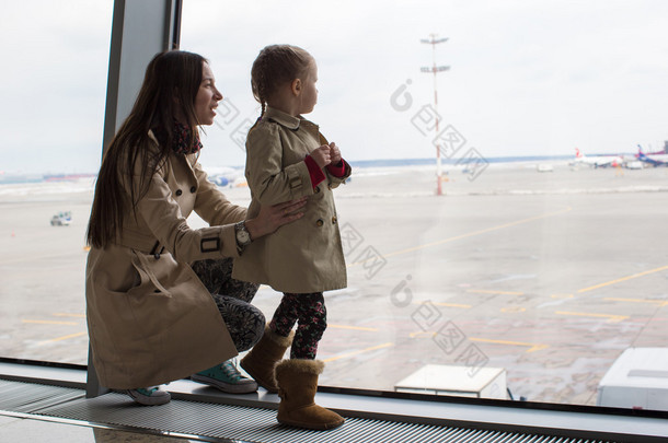 母亲和小女儿在机场航站楼窗外望去