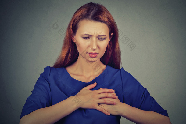 young woman with breast pain touching chest isolated on gray wall background
