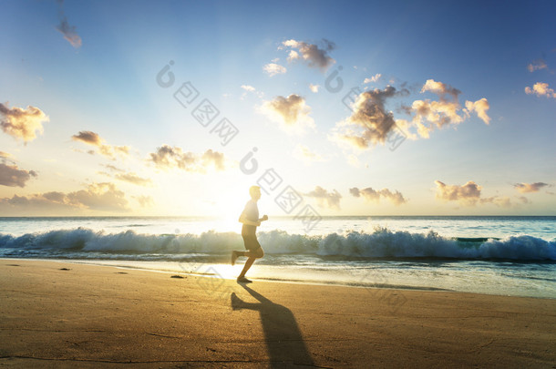 日落时在热带海滩上奔跑的人