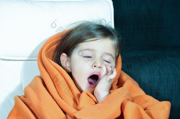 小女孩打呵欠。生病的小女孩，毯子和杯子。生病的孩子与干裂的嘴唇。小女孩与流感喝她的药.