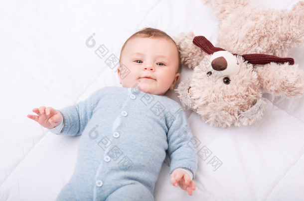 小孩躺在床上用他的玩具.