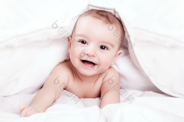 快乐和可爱的小宝贝微笑下白色的毯子.