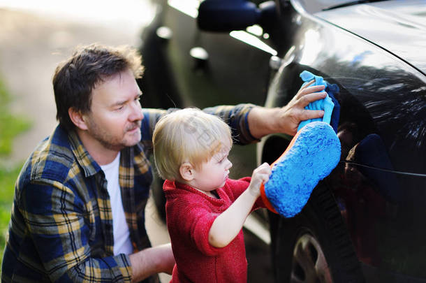 中年父亲与他蹒跚学步的儿子一起在户外<strong>洗车</strong>