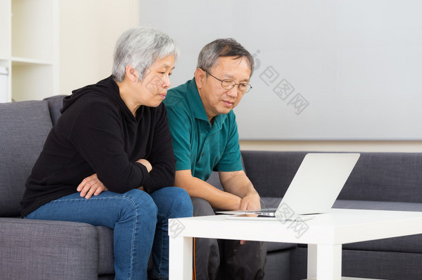 老年夫妇在家使用便携式计算机