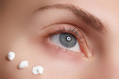 Portrait of young woman with fresh clean face with points of moisturizing  cream under the eye