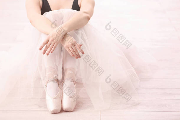 年轻的芭蕾舞演员坐在地板上
