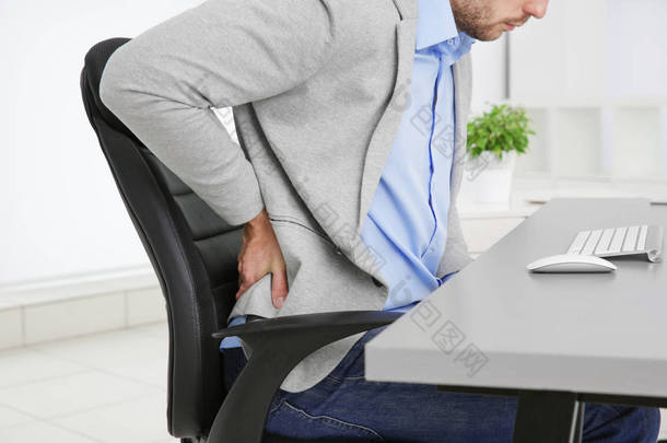在办公室，特写扶手椅上腰背痛的人