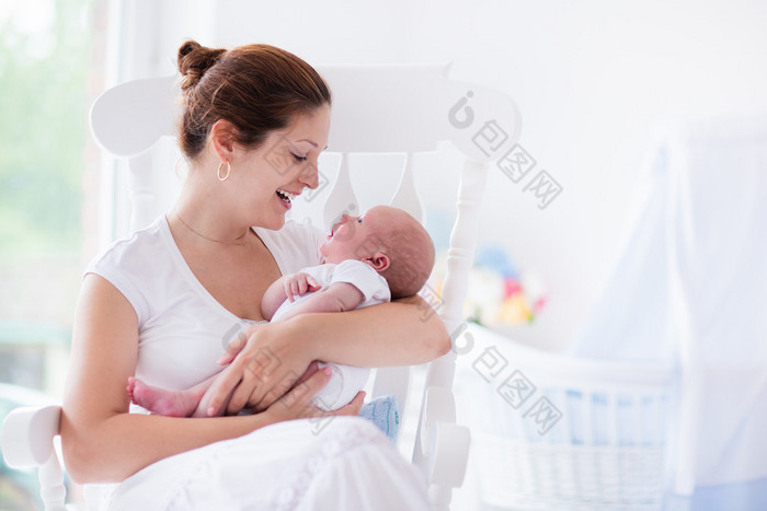 年轻的母亲和刚出生的婴儿在白色的卧室里