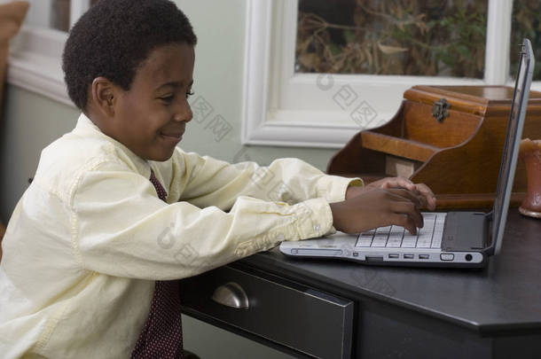 小男孩在家里在电脑上工作.