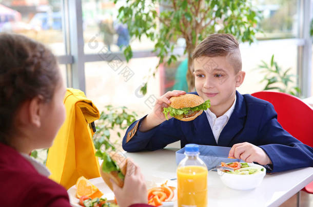 孩子们吃午饭时坐在自助餐桌旁