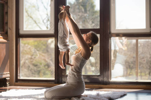 年轻魅力的运动型母亲抱着婴儿在家锻炼