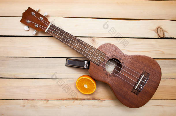 夏威夷四弦琴吉他与多汁橙橙子片和木背景上的铁唇手风琴