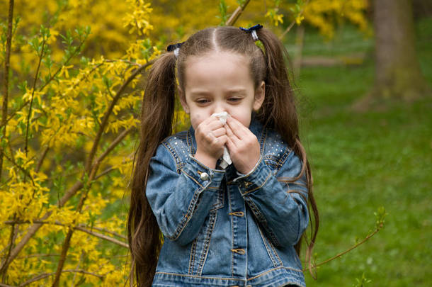 这个女孩有一个流鼻涕的鼻子。花花粉过敏.