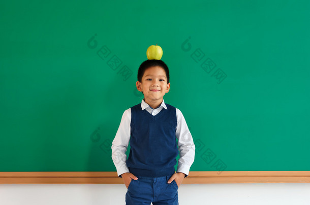 十几岁的男生在口袋里抱着双臂同时平衡在他头上的苹果