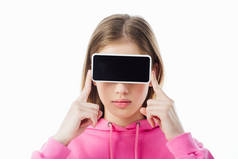 十几岁的女孩在粉红色的连帽衫举行智能手机与空白屏幕在眼睛前孤立在白色