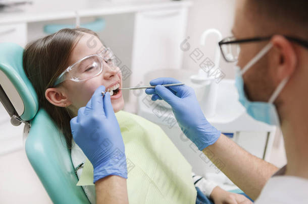 在治疗牙病的过程中，一个可爱而快乐的小女孩对着牙医笑