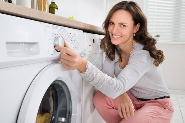 按下按钮的<strong>洗衣机</strong>的女人
