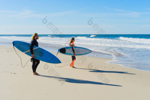 男人和女人去<strong>海边</strong>冲浪板。男人和女孩去冲浪，葡萄牙，纳扎尔。穿着湿衣服冲浪.