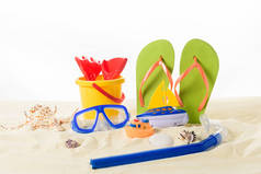 沙滩玩具和潜水面具的拖鞋在白色的沙子隔离