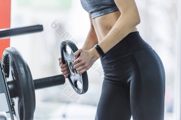 体育妇女在健身器械上添加重量板的拍摄