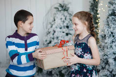 兄弟姐妹给对方一个礼物盒在圣诞树附近.