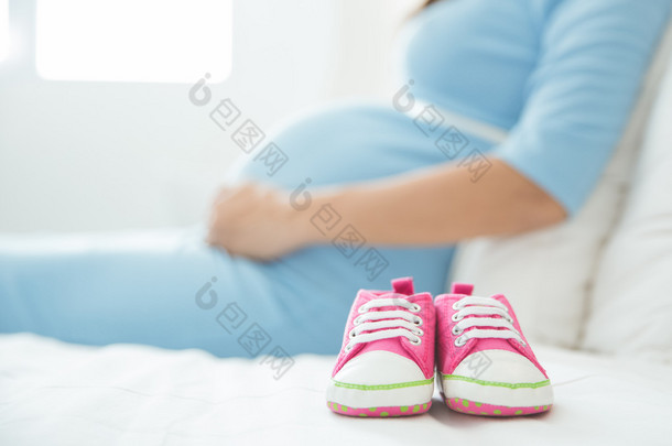 Baby Shoes with a pregnant woman on the background