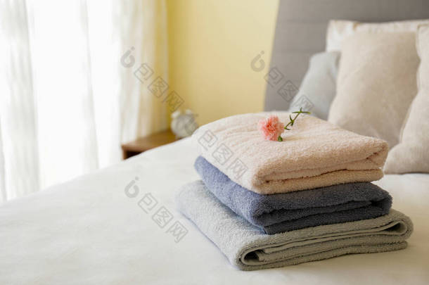 宾馆<strong>房间</strong>里有新铺的床，干净干净的熨烫过的床单，叠放着新折叠的毛巾和一朵花，作为自然光下的装饰。关闭，复制文字空间.