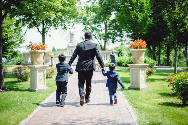 爸爸和两个小孩在公园里散步。家家户户散步快乐，户外活动愉快