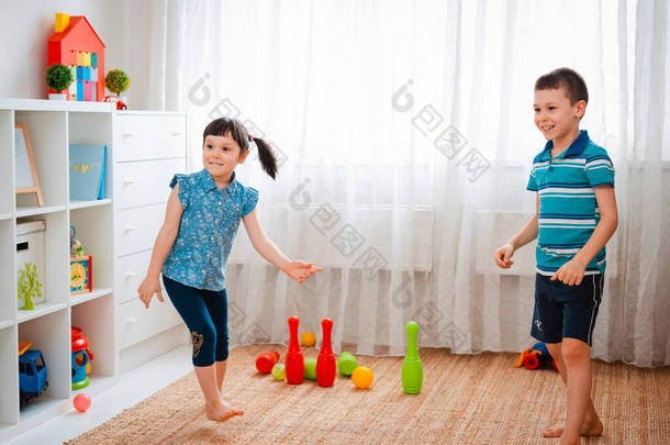 土生土长的男孩和女孩在儿童游戏室里<strong>玩耍</strong>，扔球。互动的概念兄弟姐妹，交流，相互游戏，隔离，自我隔离的家，兄妹.