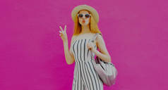 一个时髦女人的画像，带着夏日圆圆的草帽，在五颜六色的粉色背景上飘扬着甜蜜的空气之吻