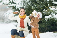 快乐妈妈和宝宝扔雪球在冬季公园