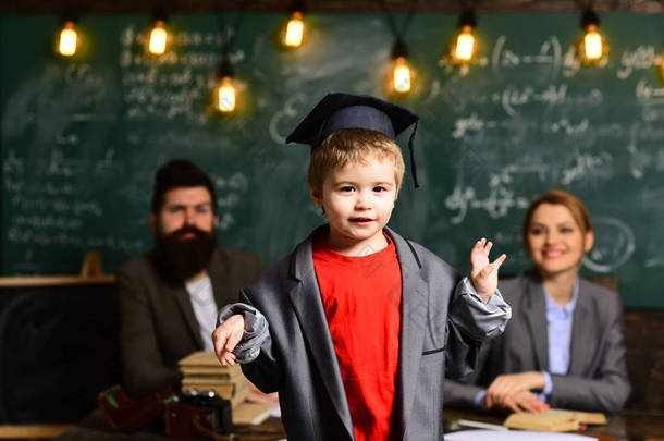 幼稚园毕业日。母亲、父亲和儿子的家庭在亲切的毕业天.