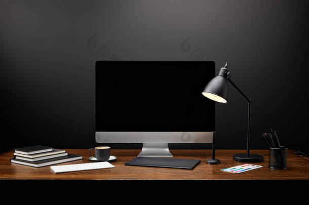 使用图形平板电脑、空白计算机屏幕、笔记本和咖啡杯在木制桌面上关闭图形设计师工作场所的视图