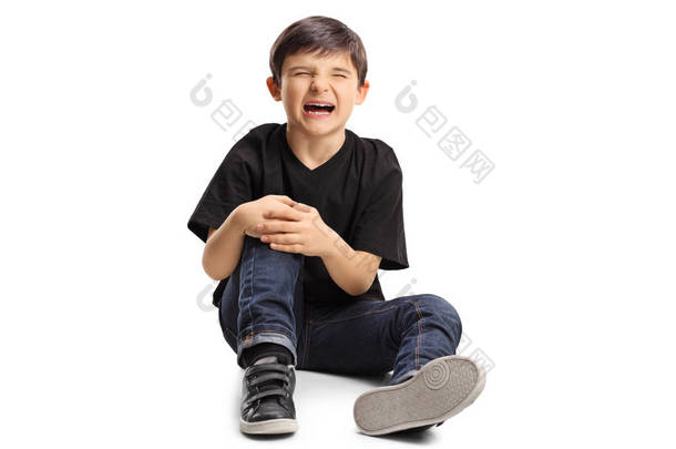 一个男孩痛苦地坐在地板上, 抱着膝盖, 在白色的背景上孤独地哭泣