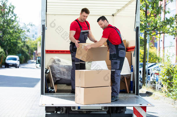 两个年轻人在移动的卡车上卸下和装上棕色纸板箱