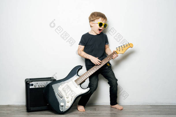 孩子们的爱好: 一个戴黑眼镜的小男孩弹电吉他, 模仿摇滚明星.