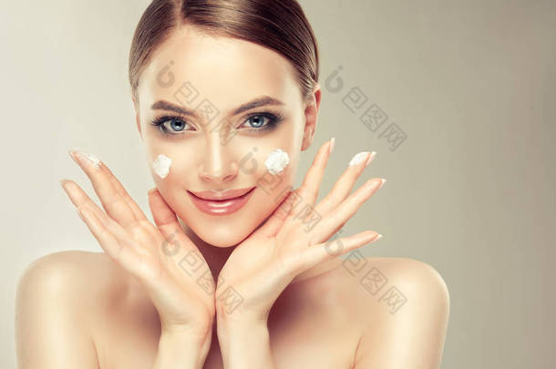 美丽的年轻女子应用化妆品奶油治疗在她的脸上孤立的背景。干净清新肌肤的女孩。<strong>水疗</strong>和美容 .
