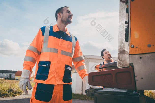 两名垃圾收集工人将垃圾装入废车
