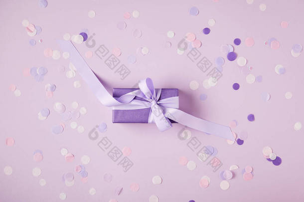 在表面上的一个紫罗兰色礼物盒和纸屑片断的上部看法